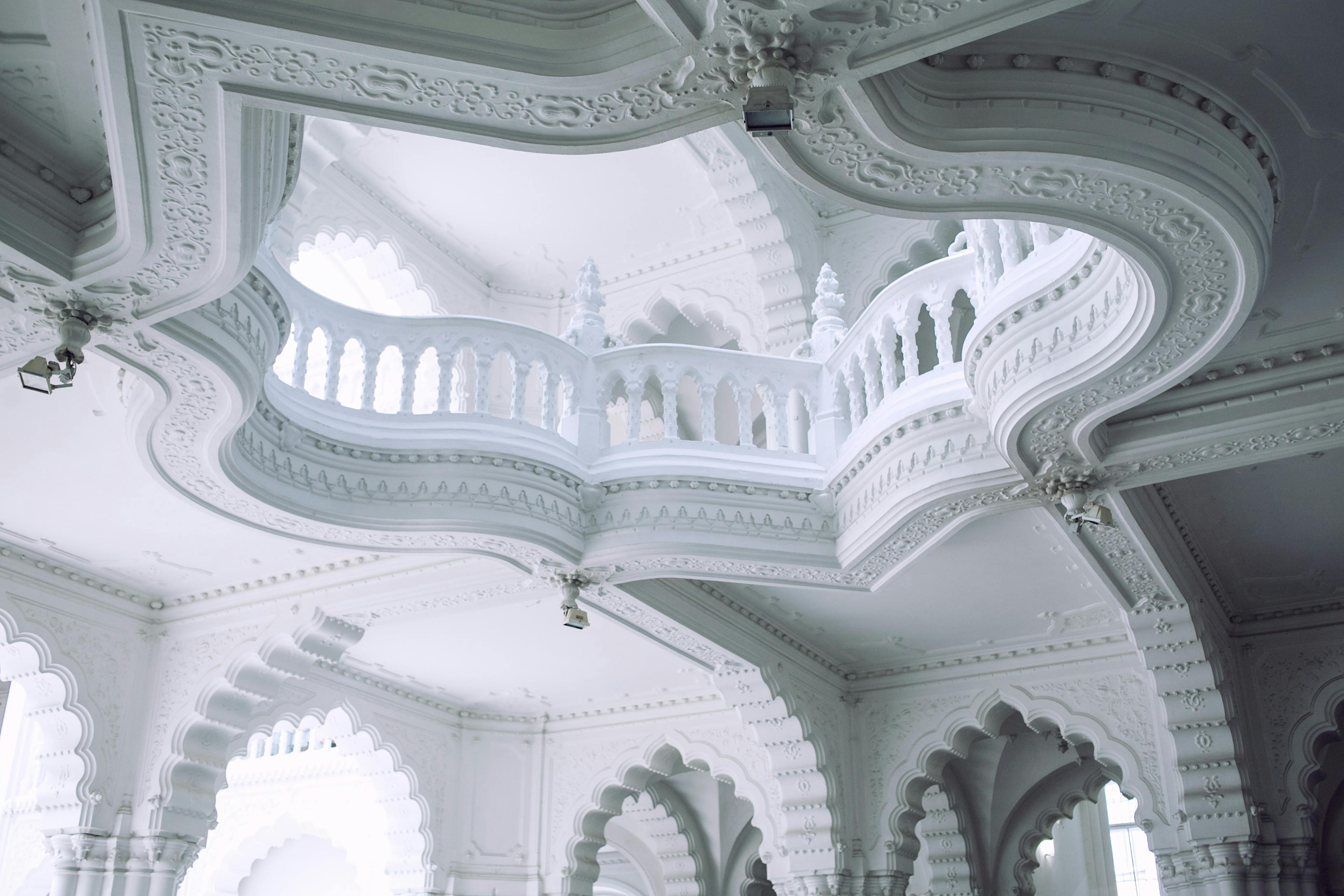 From below of old stone building interior with decorative white walls and fenced balcony in sunlight