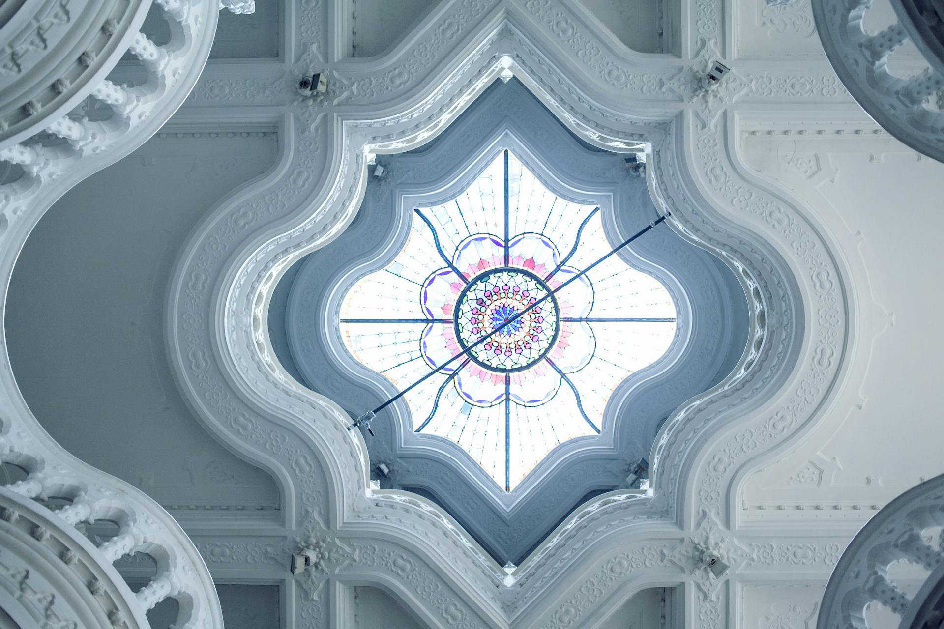 From below of classic geometric ceiling with ornamental elements and stained glass in museum