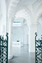 Interior of old famous museum with white ornamental elements on columns and stone floor behind fence