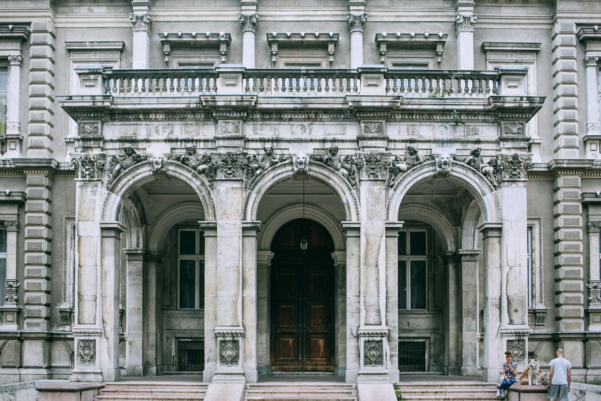 Exterior of famous palace with columns and sculptures near ornamental doorway under balcony