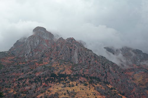 Picturesque scenery of rough rocky hills with dry vegetation in thick cloudy sky