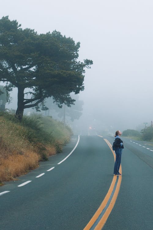 Free Faceless woman standing on empty road Stock Photo