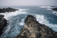海边悬崖的岩石景色壮丽，海浪强劲，地平线朦胧
