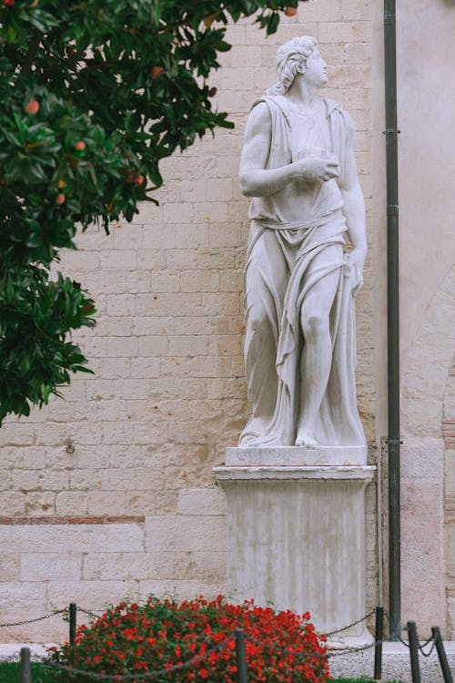Free Statue Near Old Brick Wall And Flowers Stock Photo