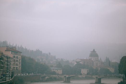 薄雾笼罩的欧洲城市景观宁静祥和，历史建筑与平静的河流尽收眼底