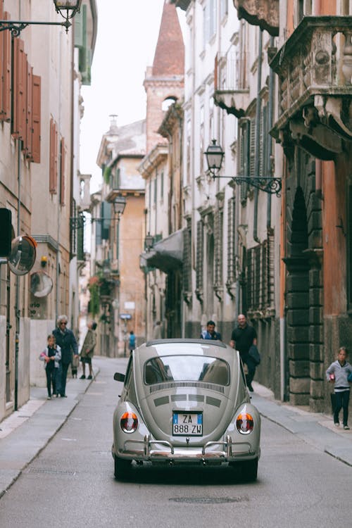 Retro car driving along narrow road in historic city