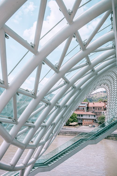 Pedestrian cantilever Bridge of Peace in geometric design with glass curved walls over river in Tbilisi Georgia