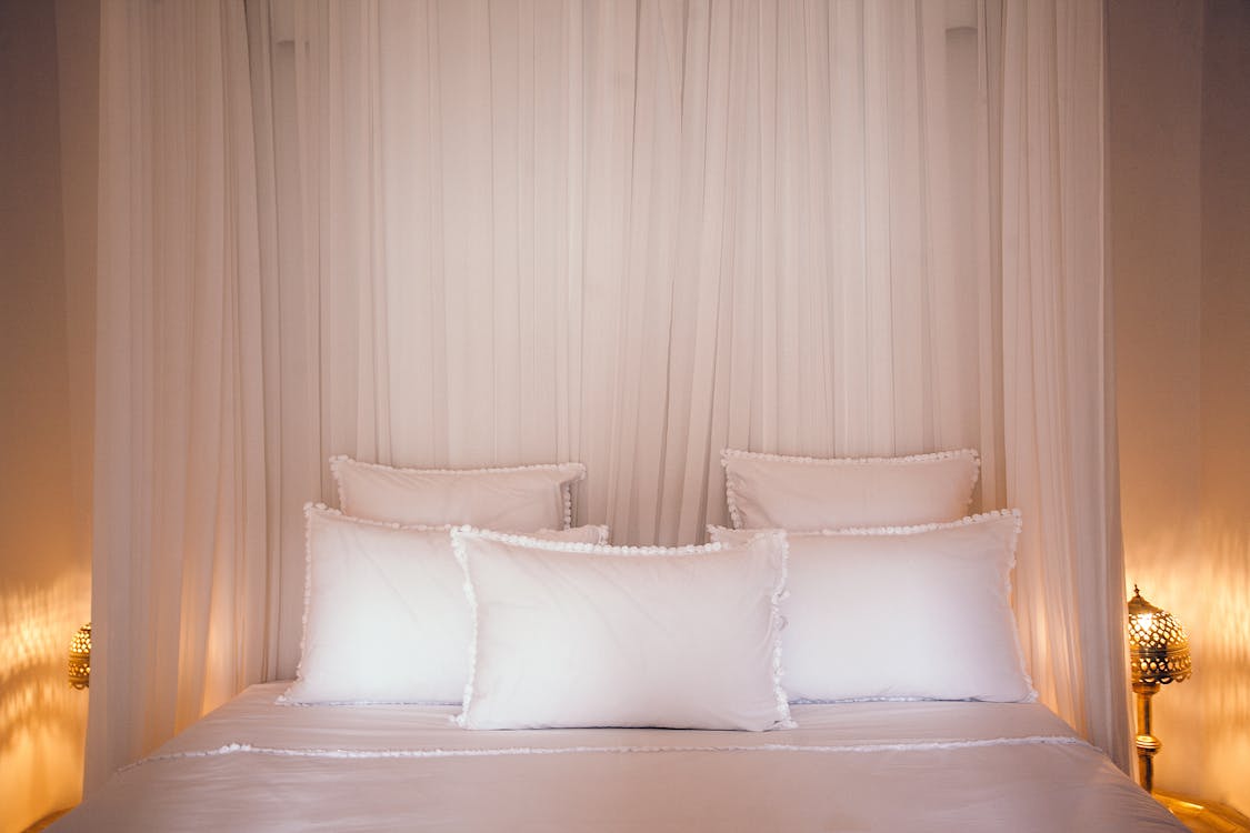 Cozy bed with pillows and white canopy