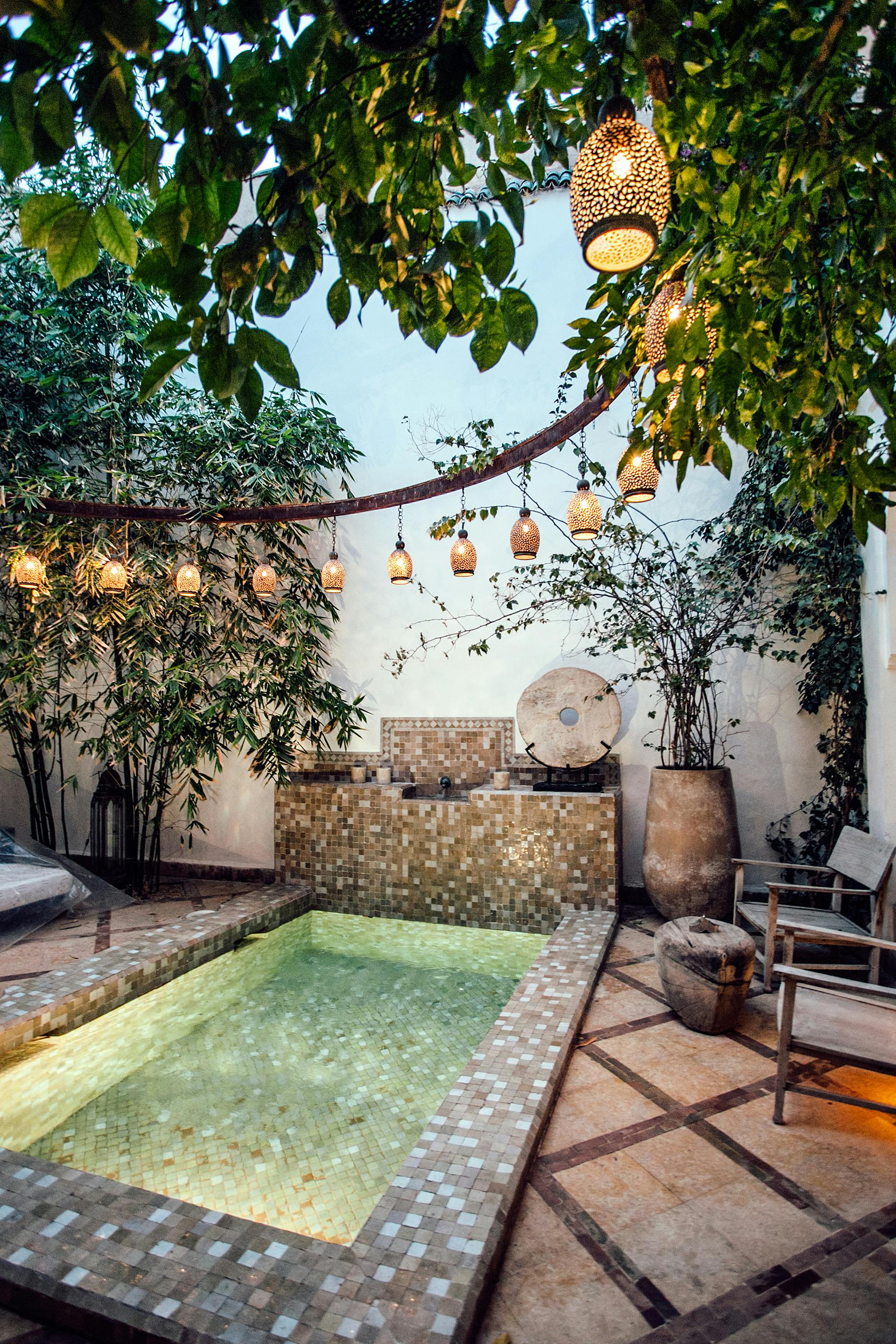 Traditional oriental hammam pool on exotic resort spa terrace decorated with lush plants and stylish lanterns