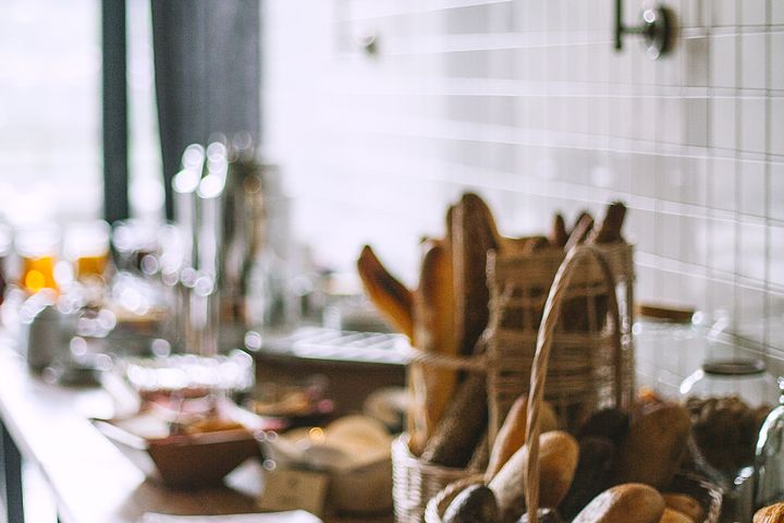 Side view of delicious fresh baked baguette and buns in wicker basket and fresh baked pies and croissant in bakery in daytime