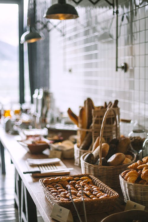 Free Side view of delicious fresh baked baguette and buns in wicker basket and fresh baked pies and croissant in bakery in daytime Stock Photo