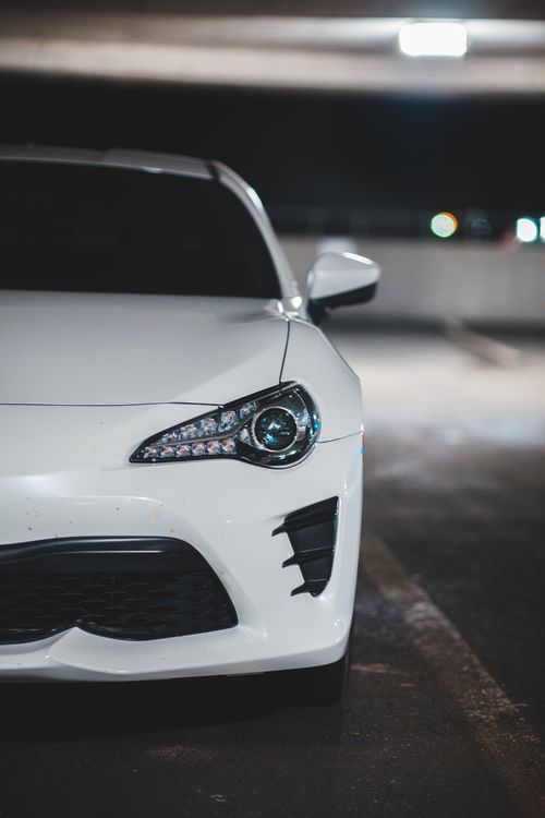 Free Shiny automobile parked on concrete surface in lights on blurred background of parking lot Stock Photo