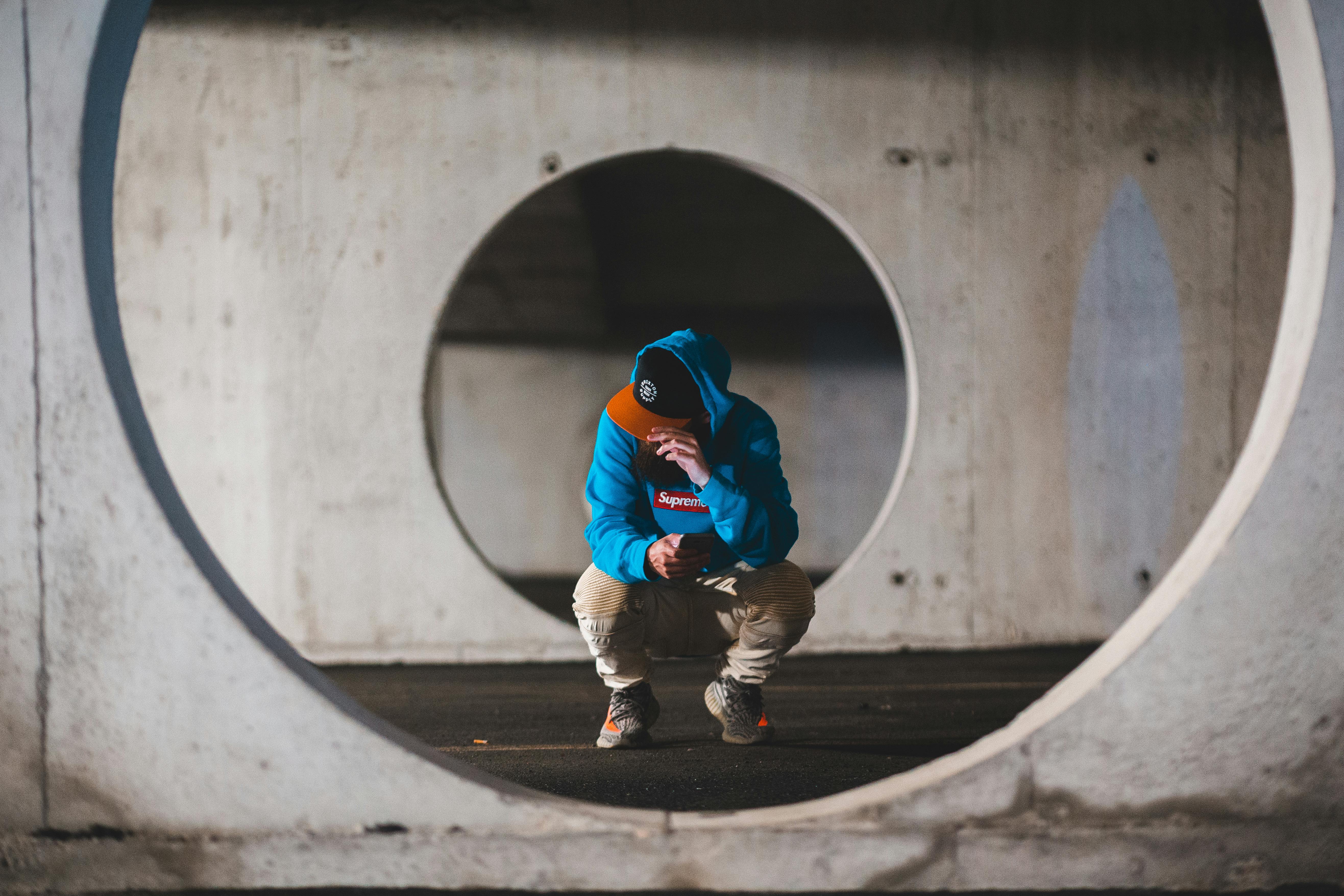 Male hipster using smartphone in concrete basement · Free Stock Photo