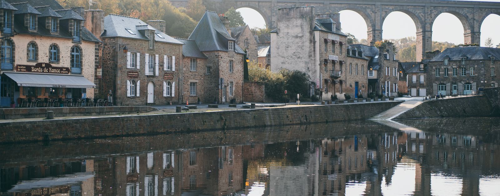 Picturesque scenery of old arched Pont Vieux masonry bridge over river flowing between ancient stone houses of Dinan medieval town located in France