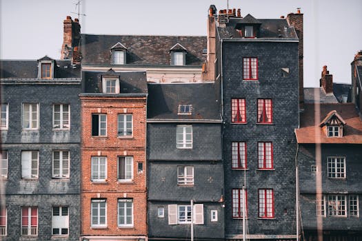 Row of old historic stone residential houses with chimneys and windows located in Honfleur town on sunny day