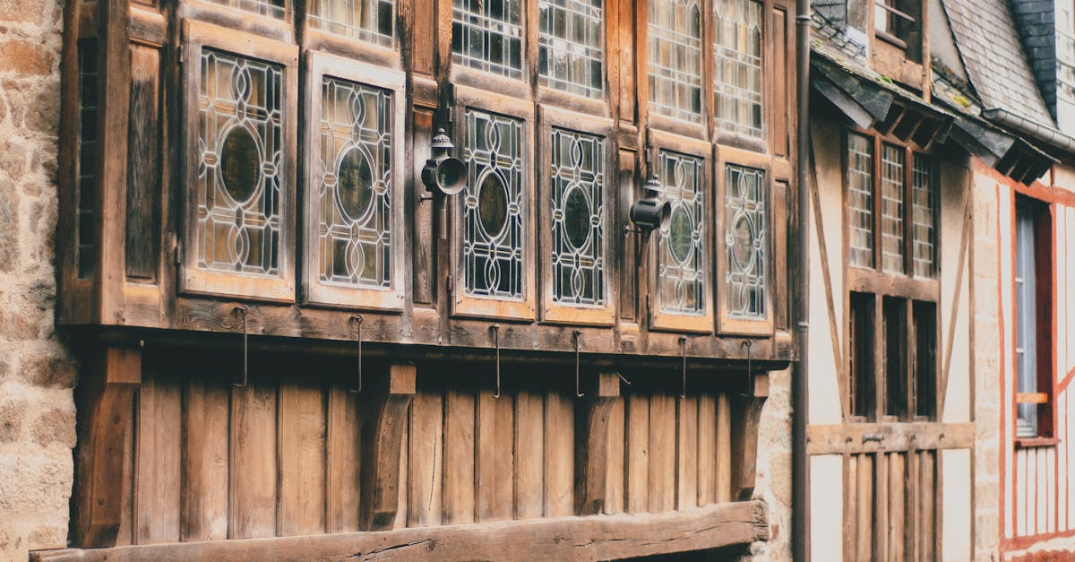 Facade of typical old stone residential houses with wooden windows and tiled roofs located on Rue de Jerzual narrow cobblestone street in medieval town of Dinan