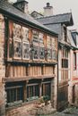 Facade of typical old stone residential houses with wooden windows and tiled roofs located on Rue de Jerzual narrow cobblestone street in medieval town of Dinan