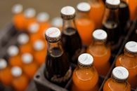 From above of glass bottles with various soft drinks placed in plastic containers on street