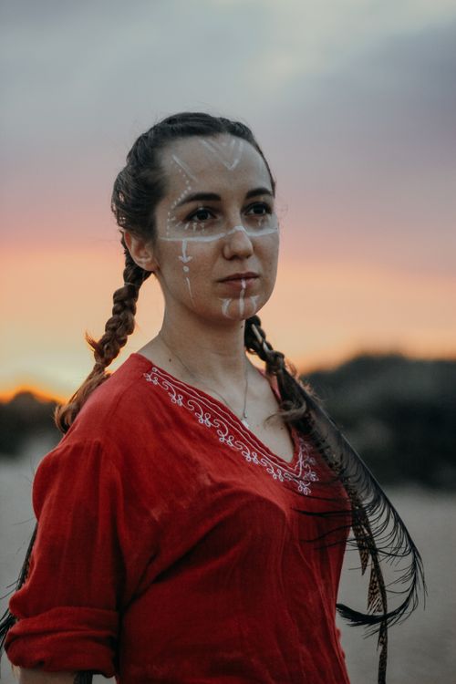 Free Portrait of a young woman in traditional attire with face paint at sunset. Stock Photo