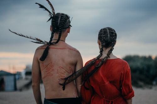 Free Couple with braided hair and body paint stands outdoors embracing love and connection. Stock Photo