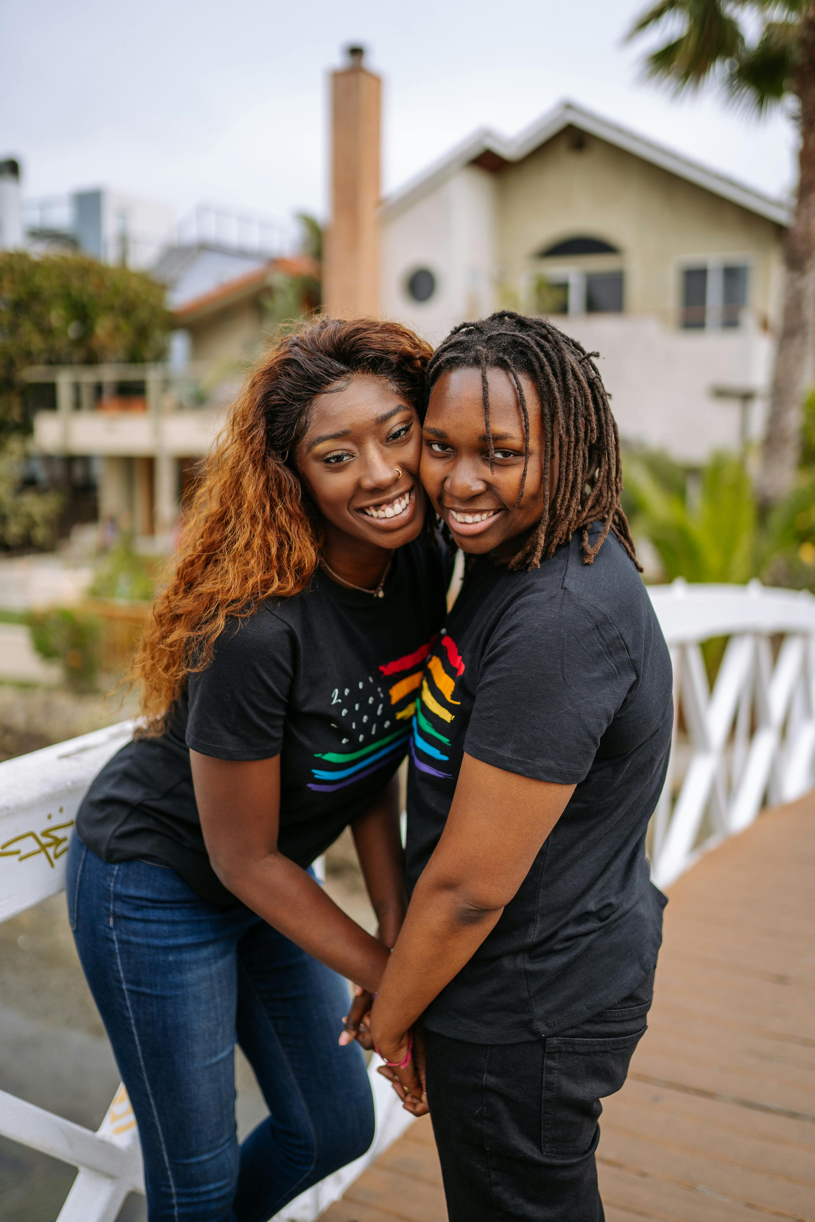 一对穿着彩虹主题衬衫的情侣微笑着并肩站在桥上，展示着爱与自豪