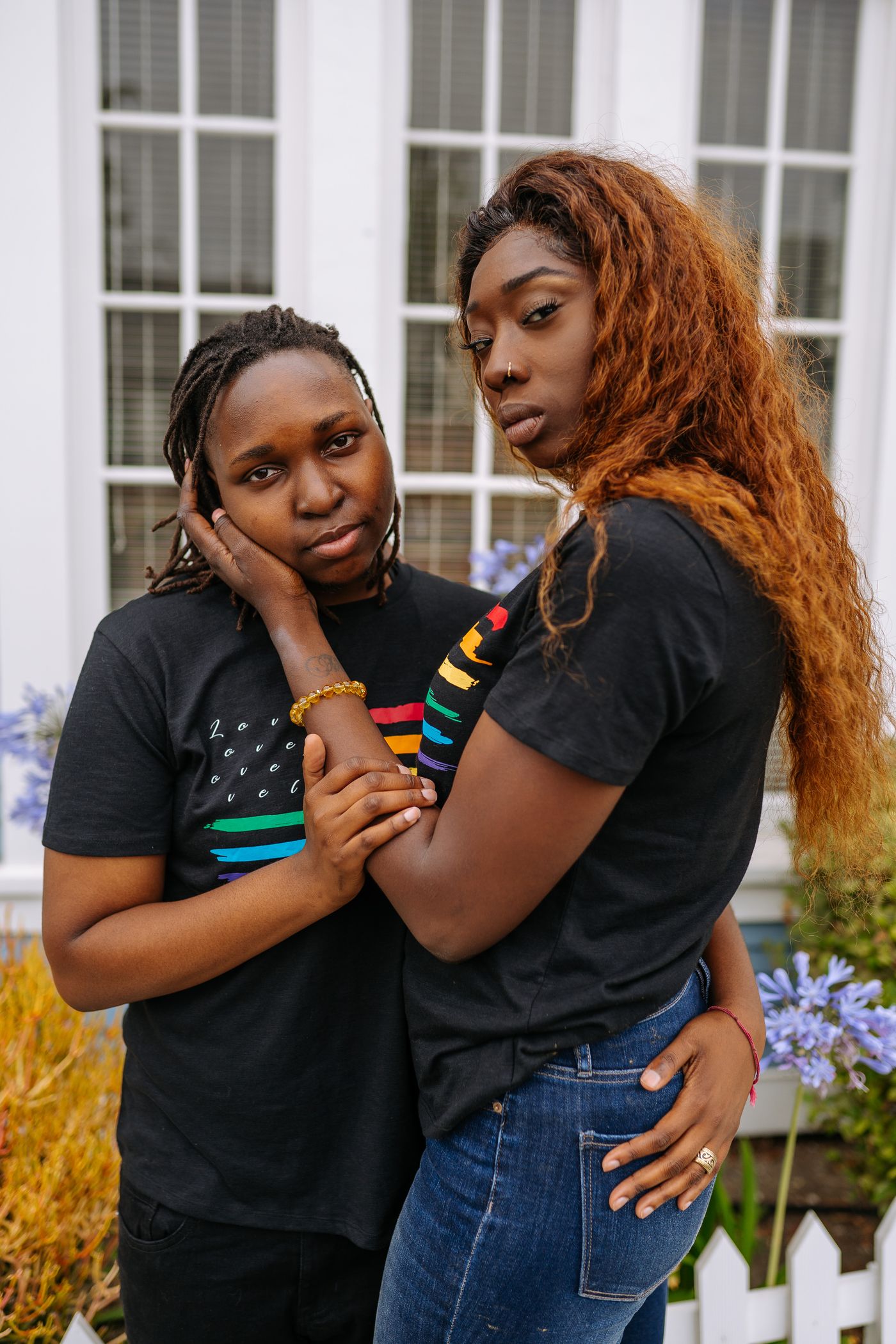 Two adult Black women embracing in a garden