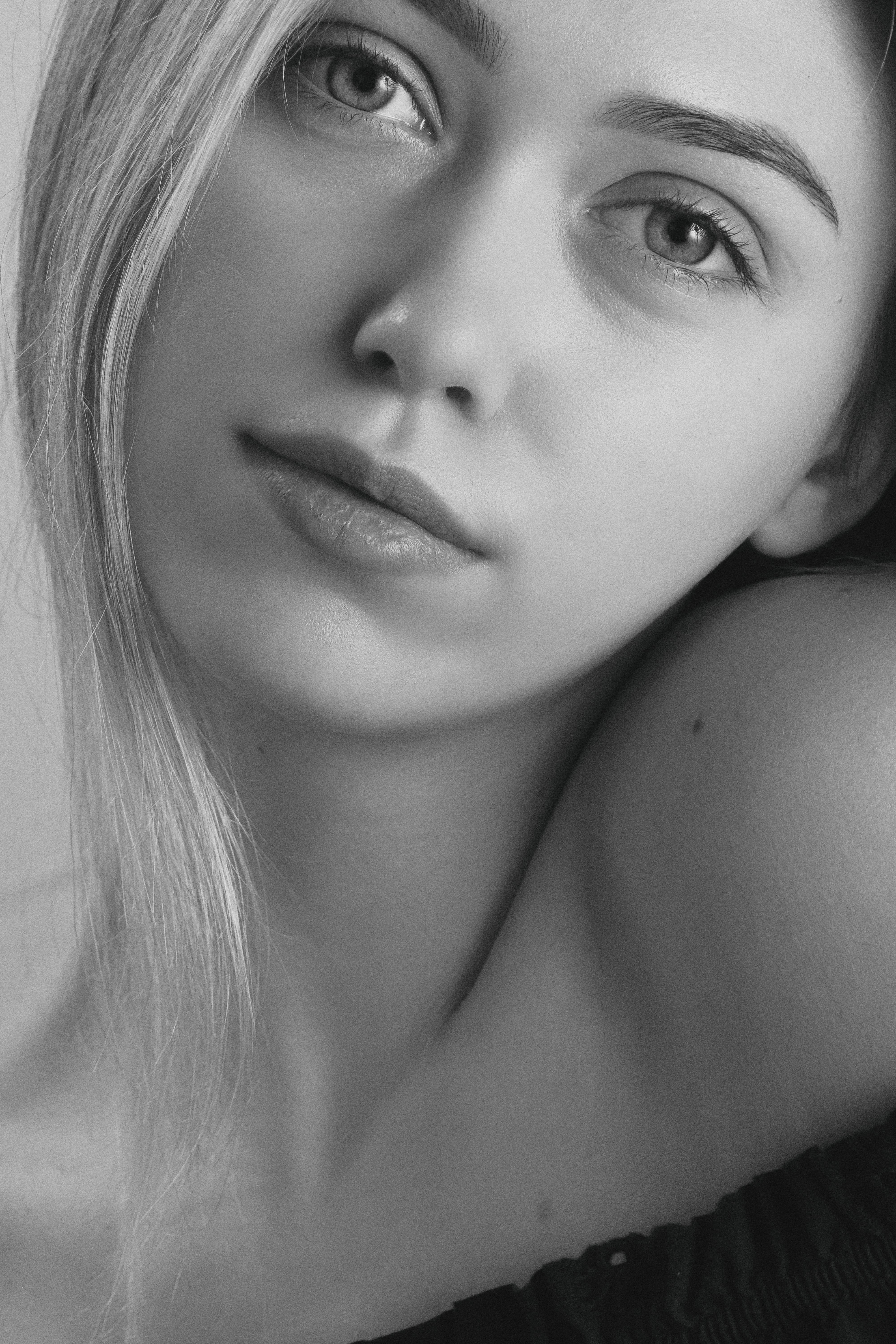Black and white close-up portrait of a young woman with soft expression.