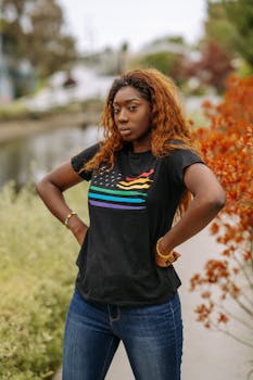 A confident woman stands outdoors in a black pride T-shirt, celebrating LGBT pride.
