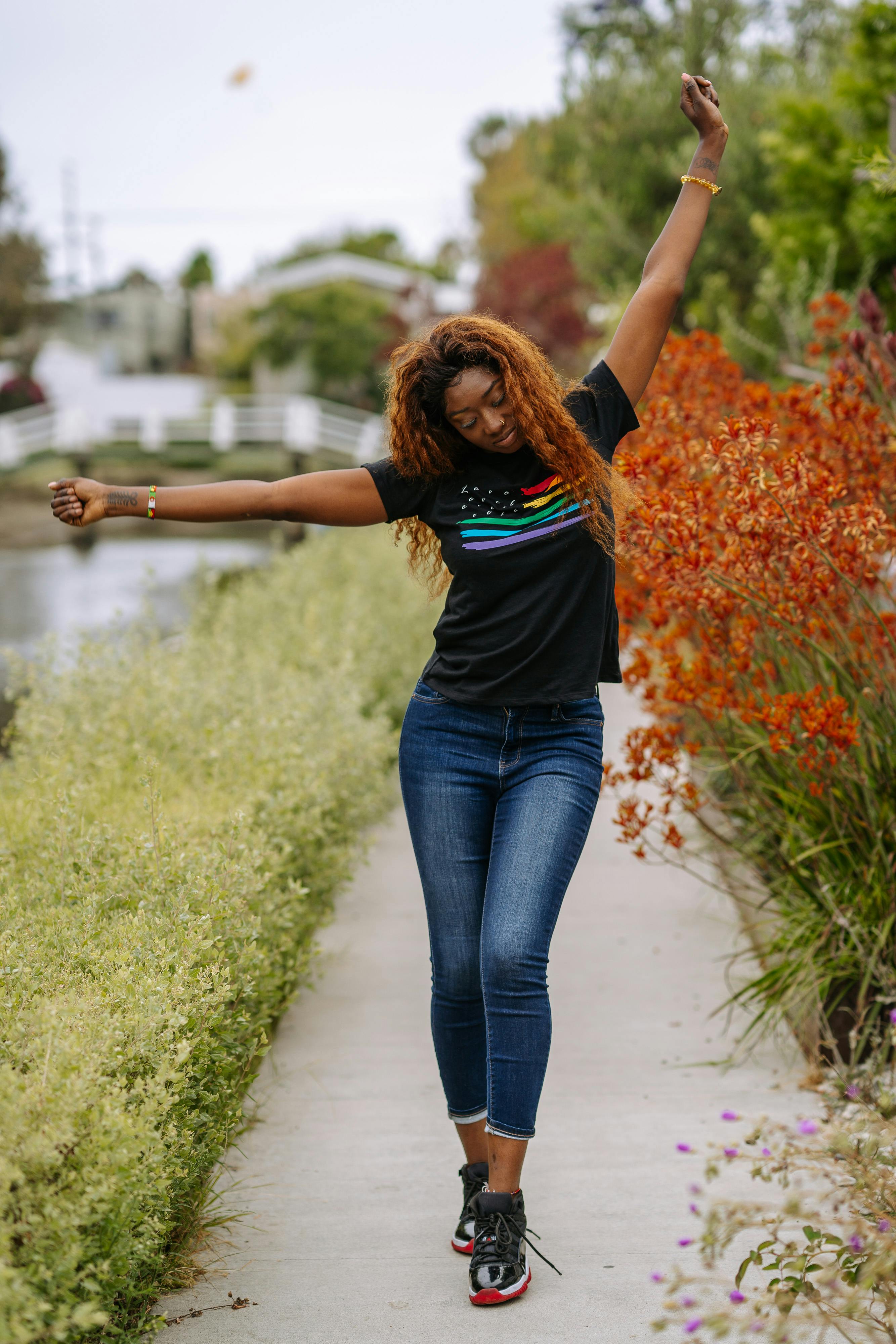 a woman in a gay pride shirt dancing in a park