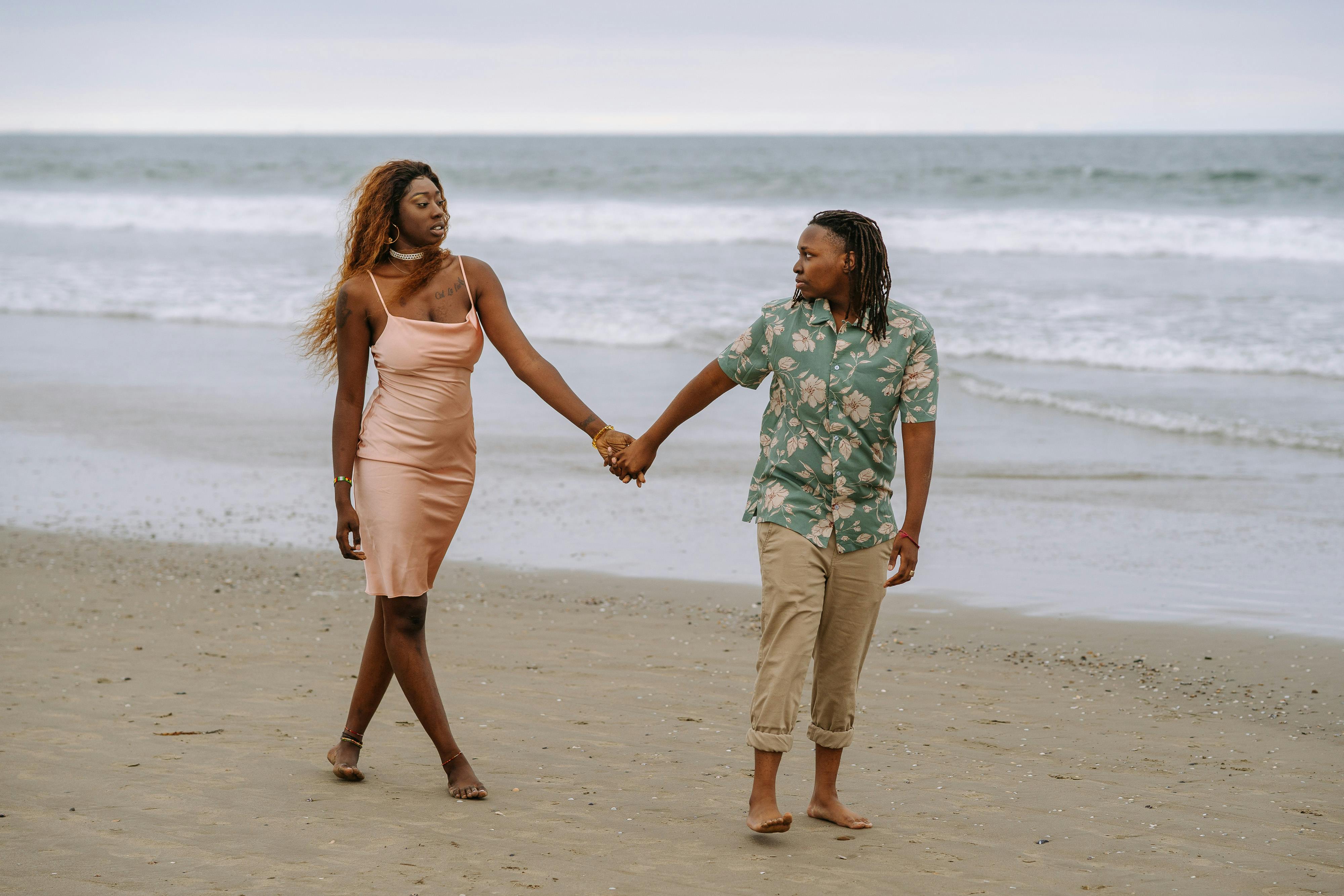 couple looking at each other while holding hands at the beach