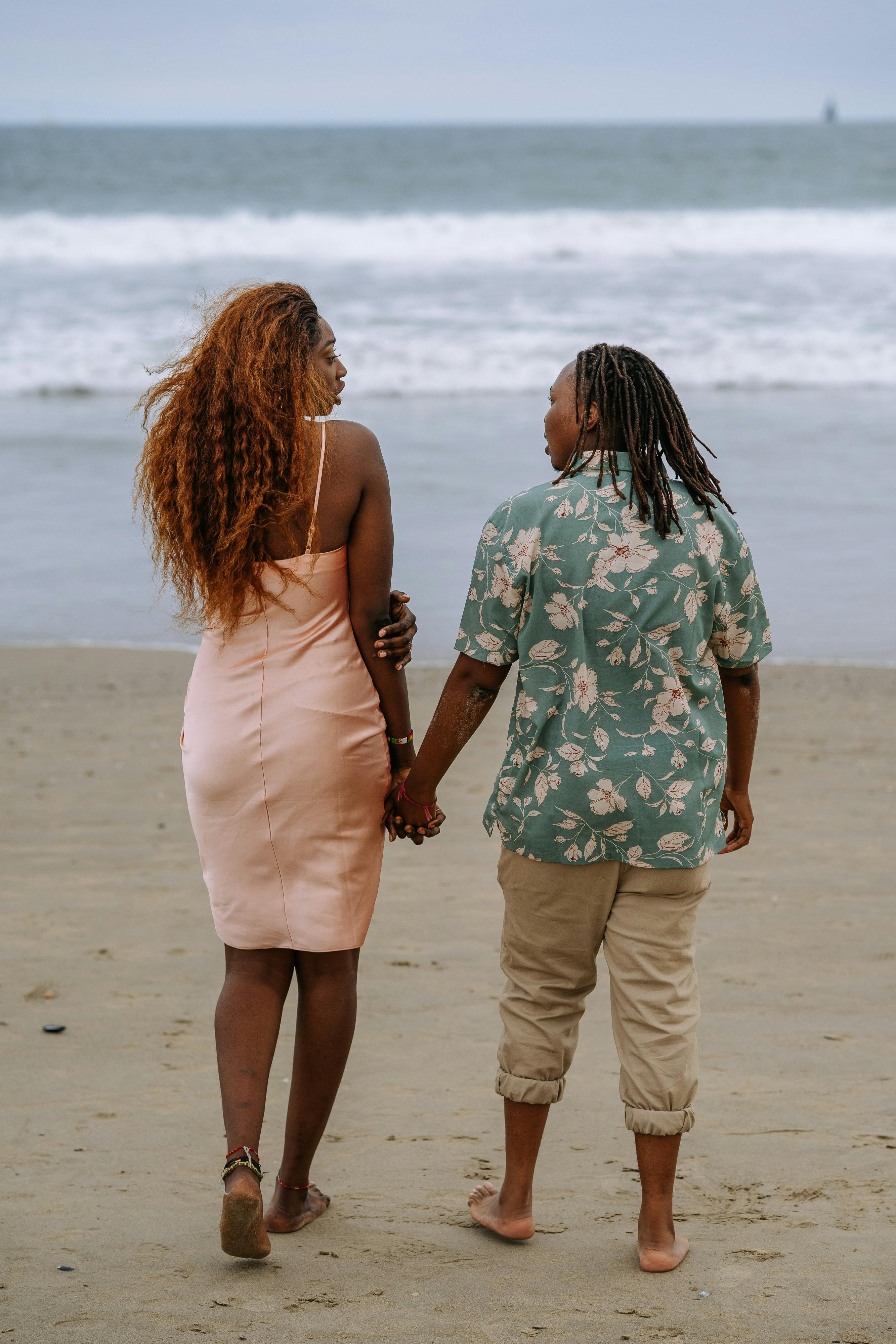 couple looking at each other while holding hands at the beach