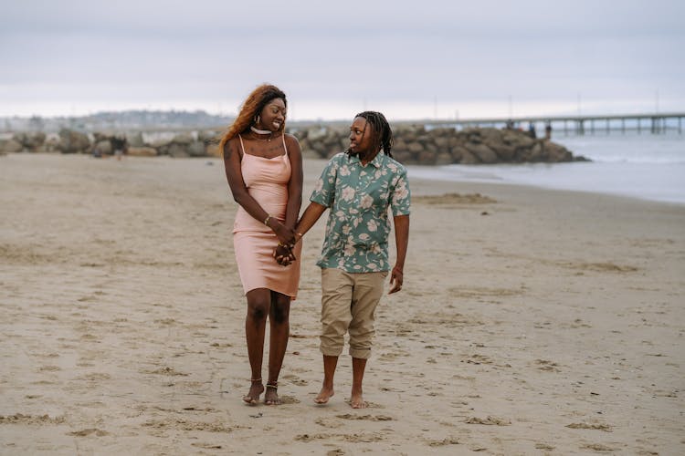 Couple Walking On The Beach While Holding Hands