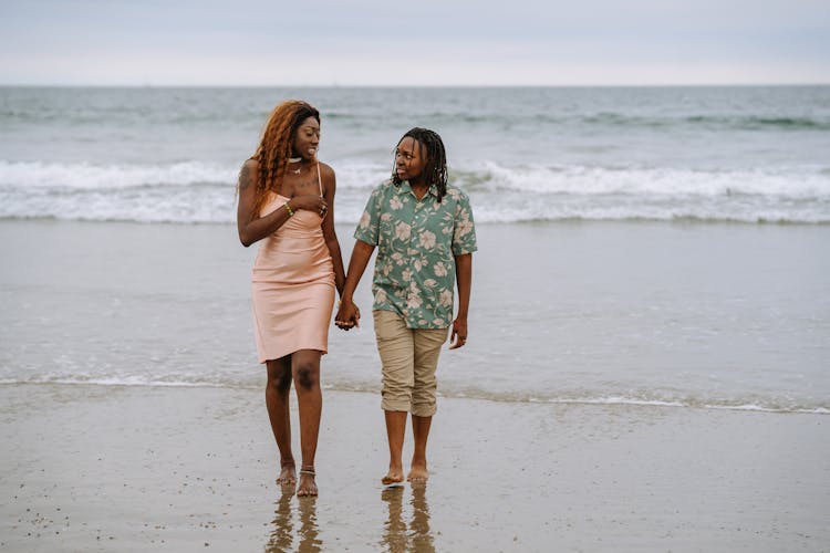 Couple Walking On The Beach While Holding Hands