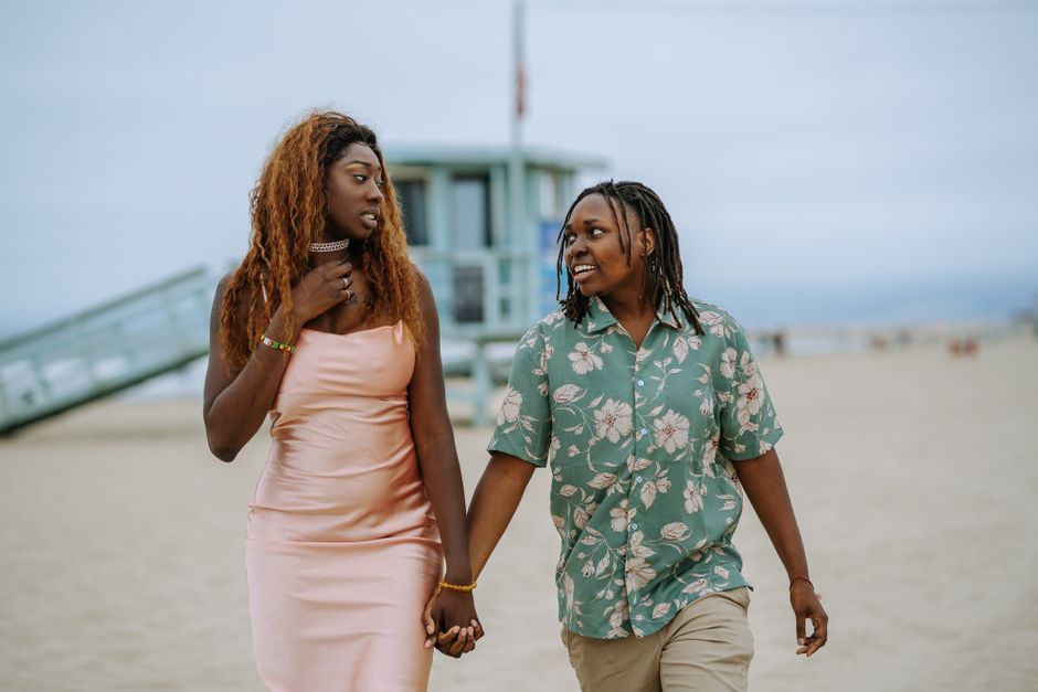 Happy couple enjoying a romantic walk on the beach, showcasing love and diversity.