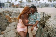 一对幸福的夫妇坐在海滩的岩石上，在户外分享爱的时刻