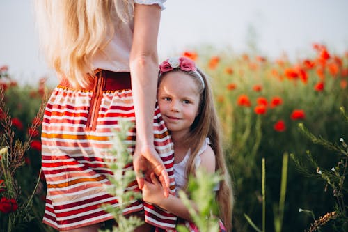 Positive girl holding hand of mother in floral field