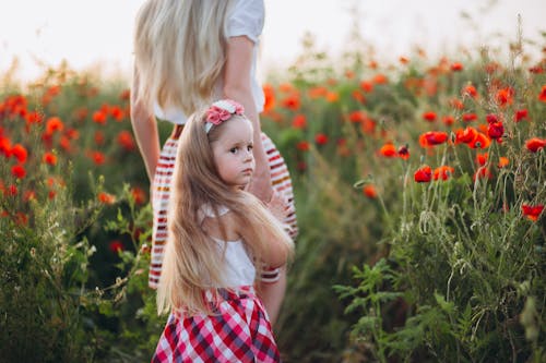 Pensive little girl holding hand of mother in field