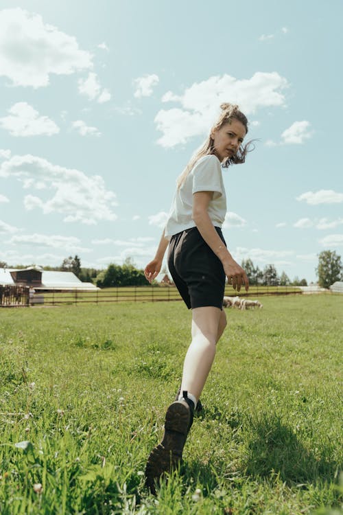 Woman in White Shirt and Black Skirt Standing on Green Grass Field