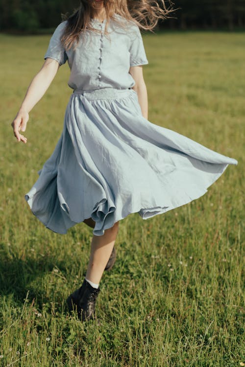 Girl in White Dress Walking on Green Grass Field