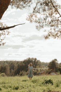 一位身着夏装的女人，在明亮的天空下走过郁郁葱葱的草地