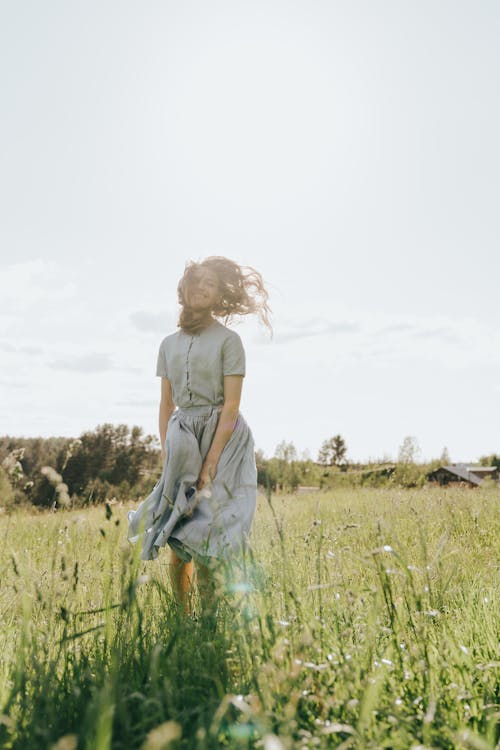 Girl in Gray Tank Top Walking on Green Grass Field