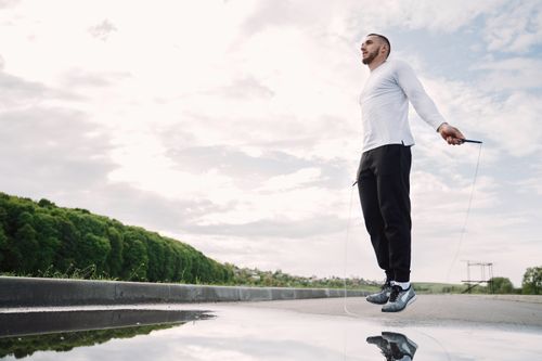 Free A man engaged in outdoor fitness by skipping rope, promoting active lifestyle. Stock Photo