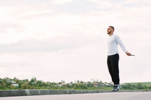 Free Man performing jump rope exercise outdoors for fitness and healthy lifestyle. Stock Photo