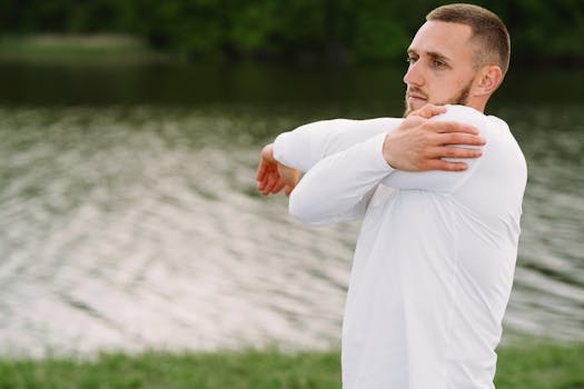 Adult man stretching by a lake, promoting a healthy lifestyle and exercise outdoors.