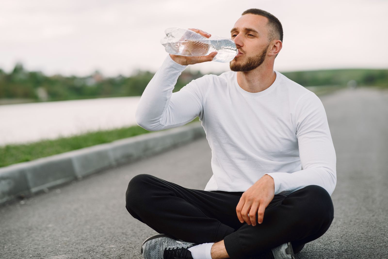 A person drinking water from a bottle to stay hydrated.