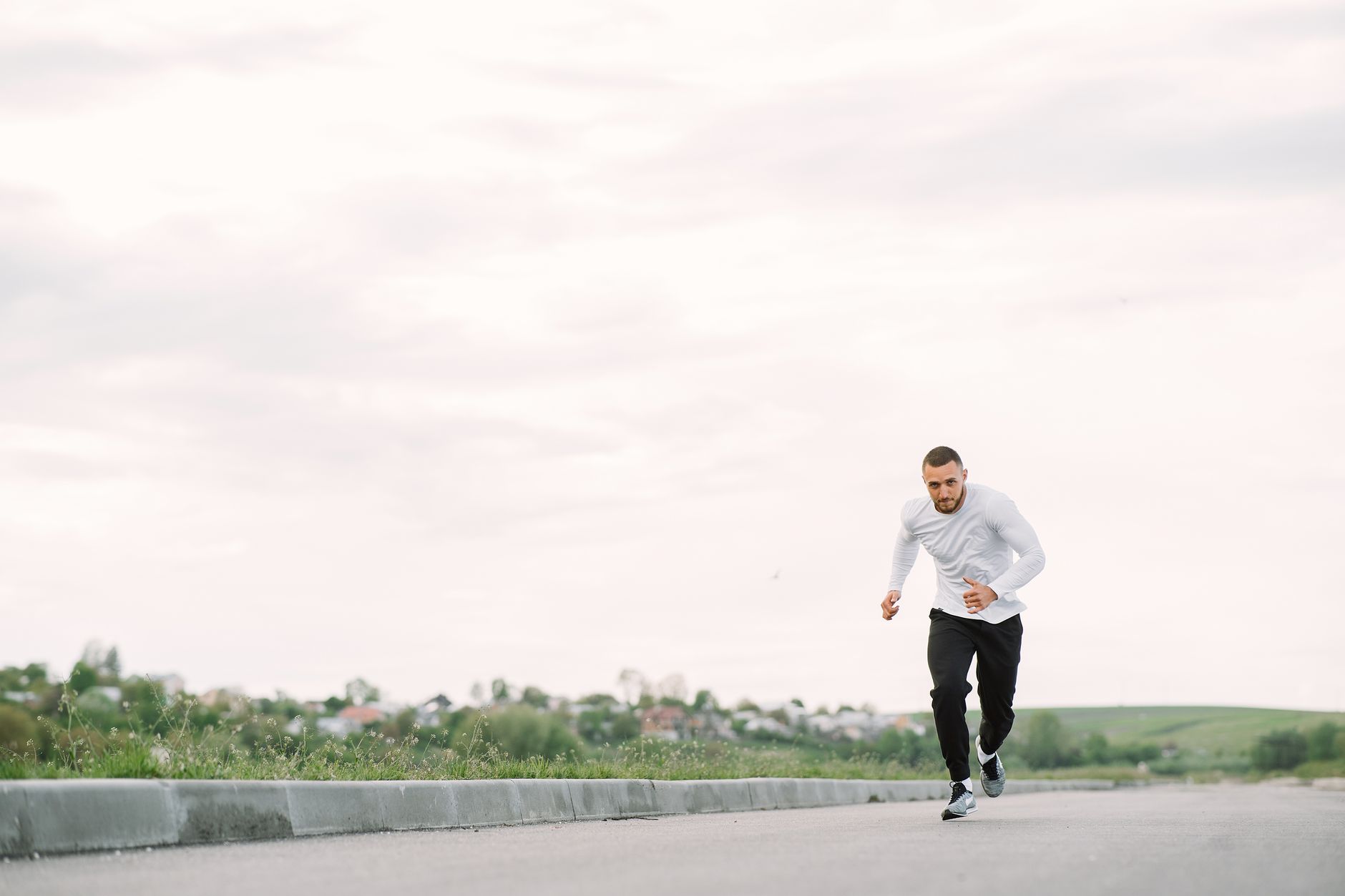 A man in sportswear jogging on a road, showcasing outdoor fitness.