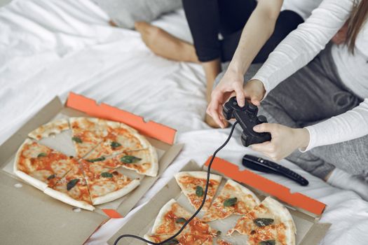 Two people enjoy pizza and gaming, creating a cozy indoor vibe.