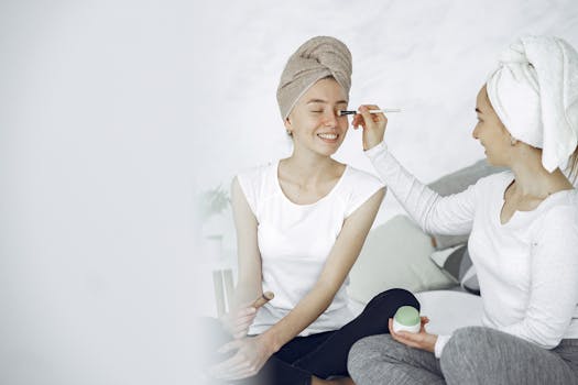 Two women enjoy a home spa day, applying makeup and bonding over beauty routines.