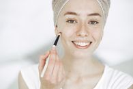 女人微笑着用刷子化妆，特写镜头突显了自然美