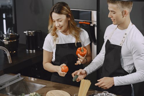 Man and Woman standing beside a Kitchen Sink 